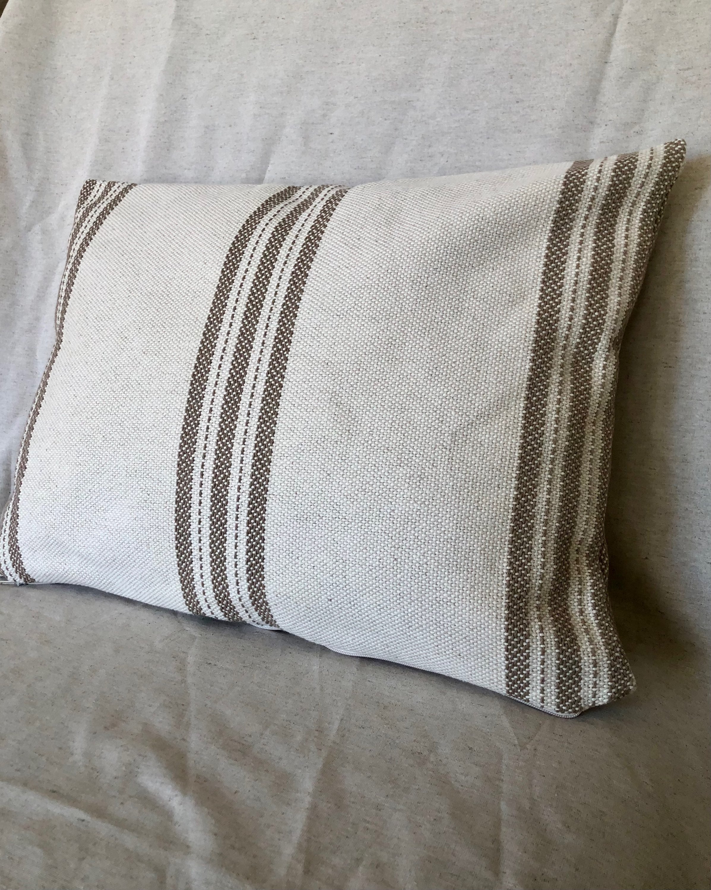 Funda de cojines en un sofá de color gris y estampado rayado