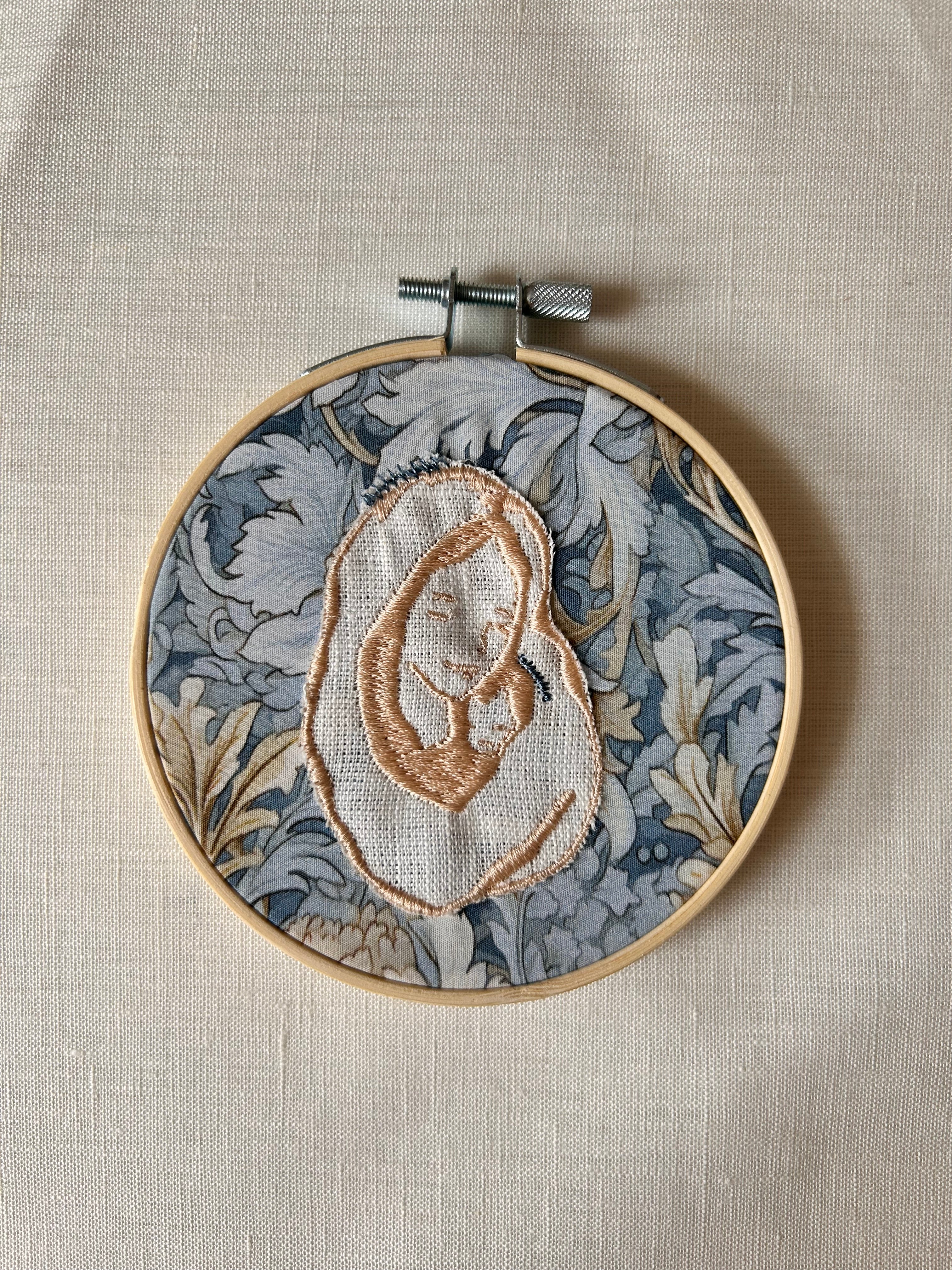 Virgen bordada sobre tela de color amarillo sobre azul claro